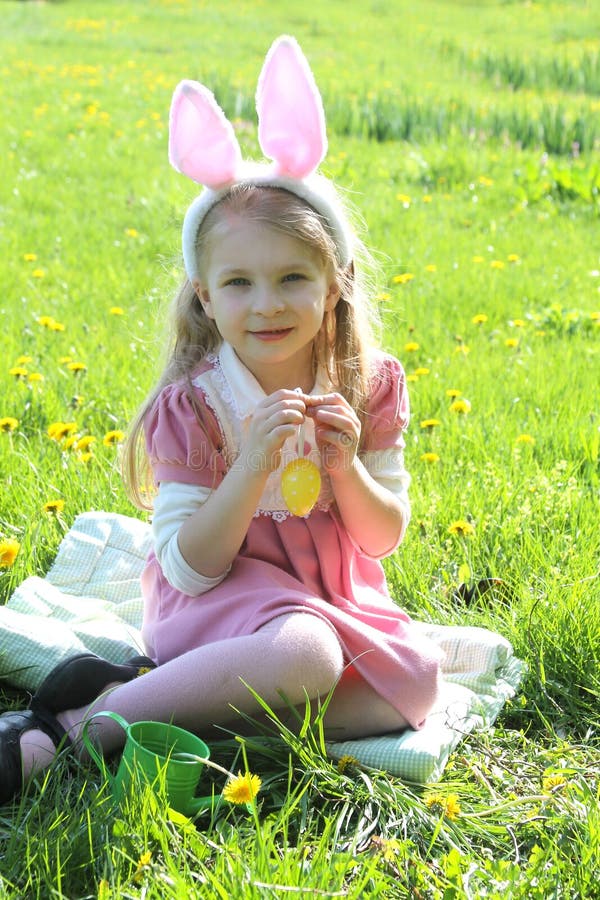 Cute girl with bunny wearing ears at spring green grass