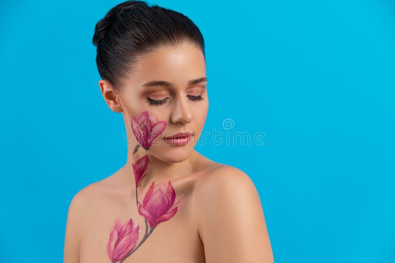 Cute girl with dark hair, body art paintings on neckline and face, naked shoulders, painting magnolia flowers, make up royalty free stock images Cute girl with dark hair, body art paintings on neckline and face, naked shoulders, painting magnolia flowers, make up royalty free stock images