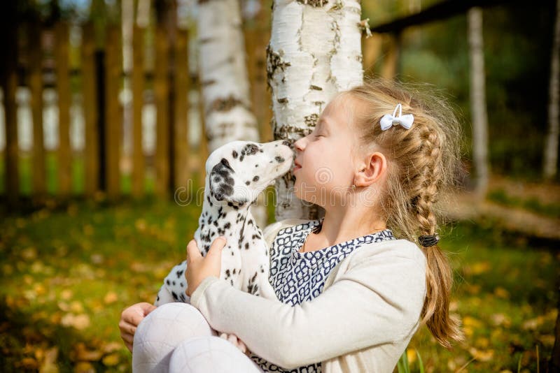 Cute girl kissing her puppy, doggy on the wood fence background.Happy girl with a dog licking her face.real friends royalty free stock images Cute girl kissing her puppy, doggy on the wood fence background.Happy girl with a dog licking her face.real friends royalty free stock images