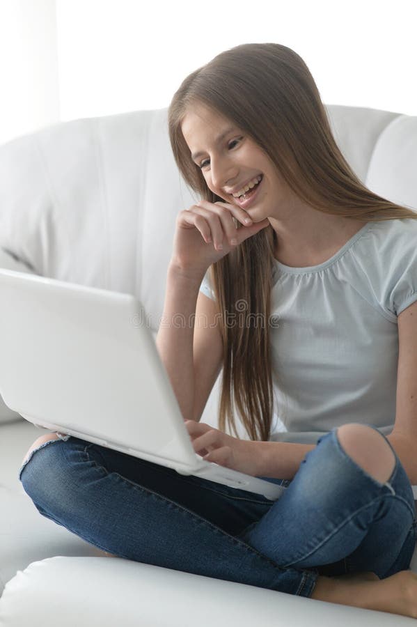 Cute girl with laptop on sofa at home