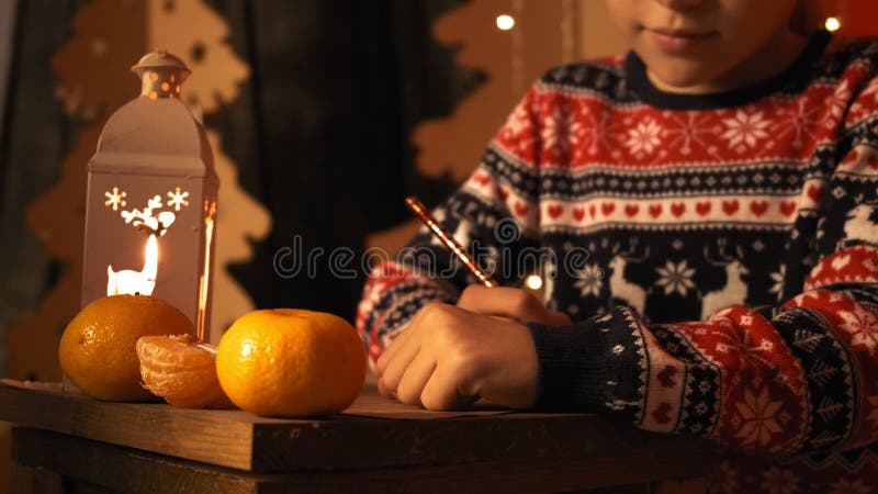 Cute girl in a New Year`s sweater writes a New Year`s wish to Santa Claus in slow motion