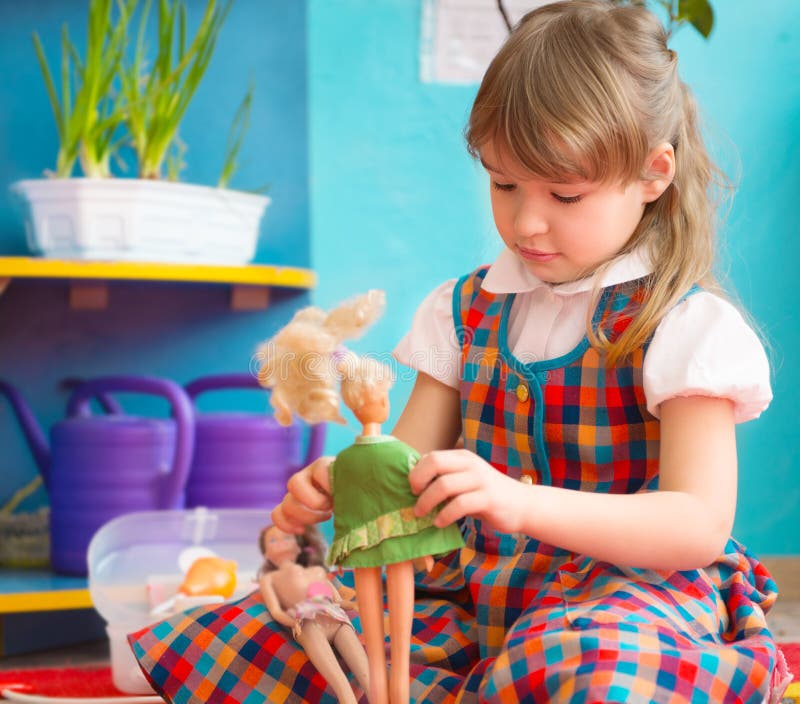 Cute girl playing with toy doll at kindergarten