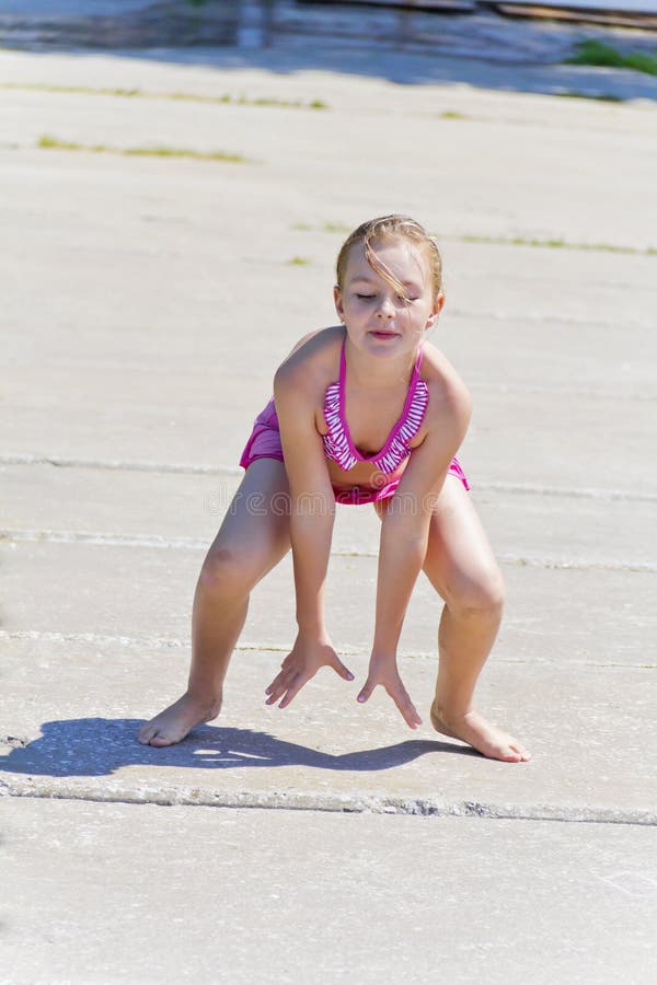 Cute girl on the riverbank in pink swimsuit royalty free stock photography Cute girl on the riverbank in pink swimsuit royalty free stock photography