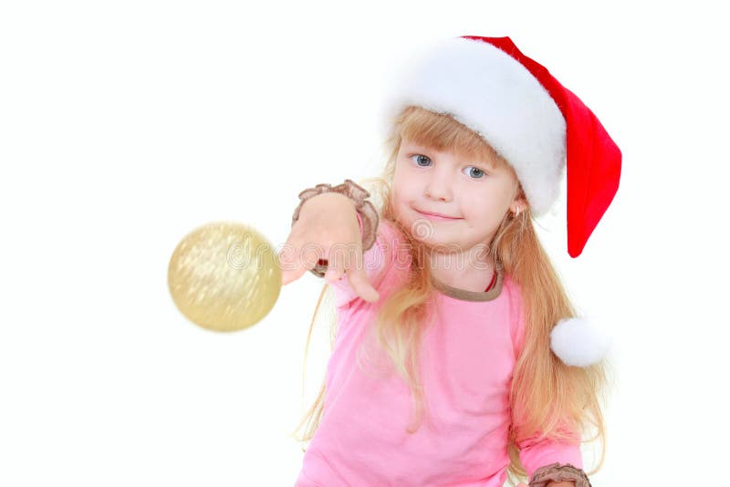 Cute girl in santa hat throing gold ball