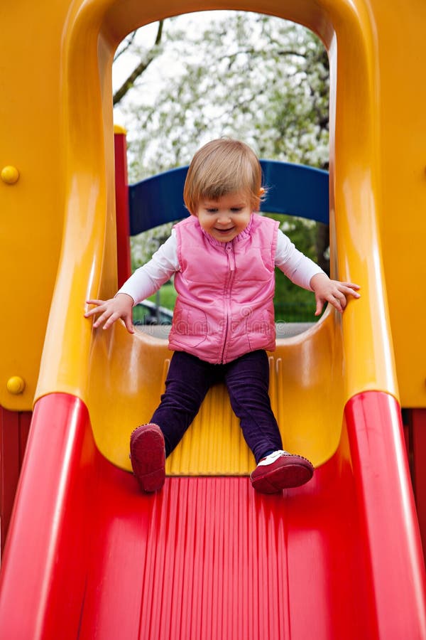 Cute girl sitting at yellow slide