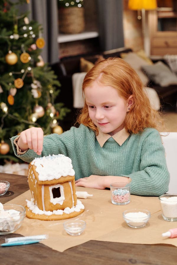 Cute Girl Sprinkling Roof of Gingerbread House Decorated with Whipped ...