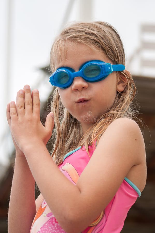 Cute girl in swimming glasses and swimsuit, going to dive into the water royalty free stock photo