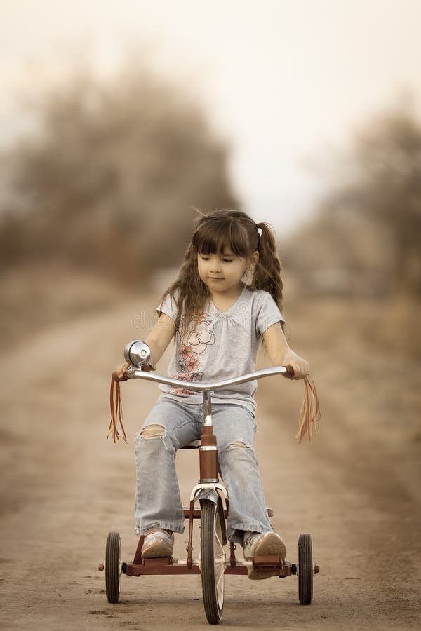 Lindo pequeno un nino sobre el caballo triciclo sobre el suciedad carreteras la esquina.