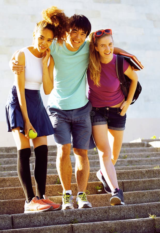 Cute group of teenages at the building of university with books huggings, back to school