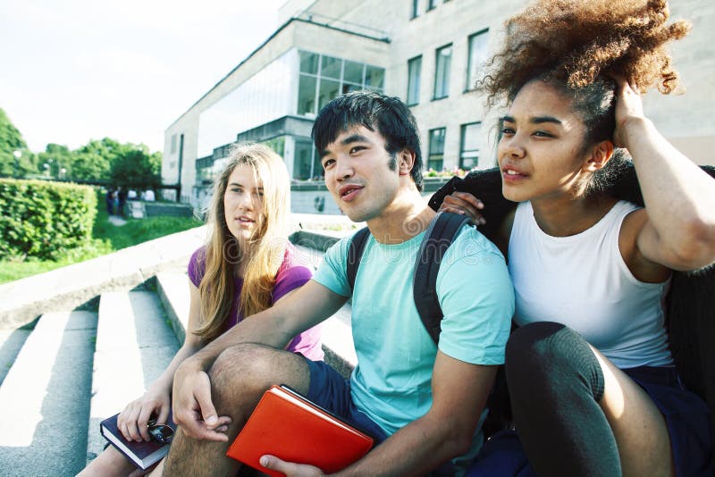 Cute group of teenages at the building of university with books huggings, diversity nations real students lifestyle