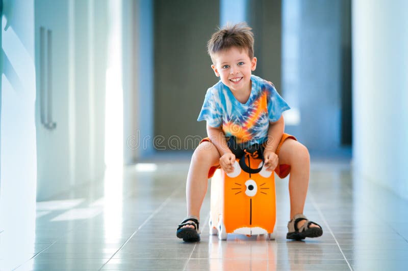 Roztomilý tri roky starý chlapec smeje na kufor na letisko.