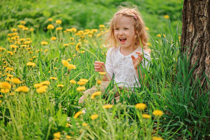 Cute happy child girl on dandelion flower field