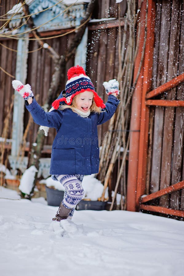 Cute happy child girl having fun and throwing snow in winter garden