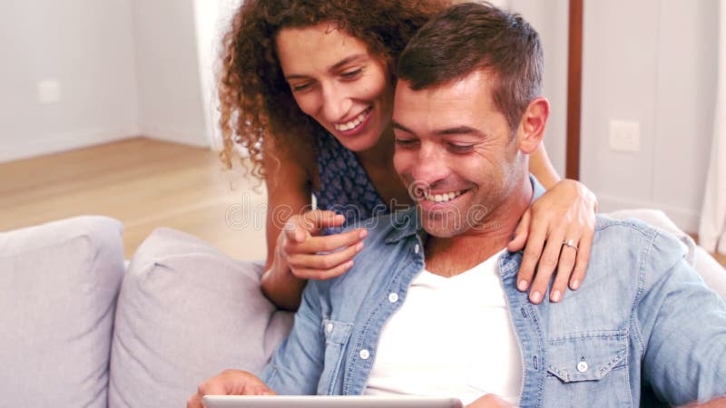 Cute happy couple using tablet on the couch