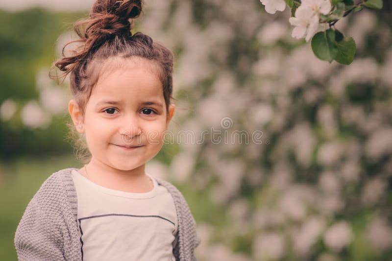 Cute happy dreamy toddler child girl walking in blooming spring garden, celebrating easter outdoor