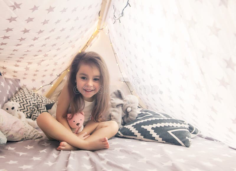 Cute happy little girl playing with toys and dreaming in teepee and bed. stock photography Cute happy little girl playing with toys and dreaming in teepee and bed. stock photography