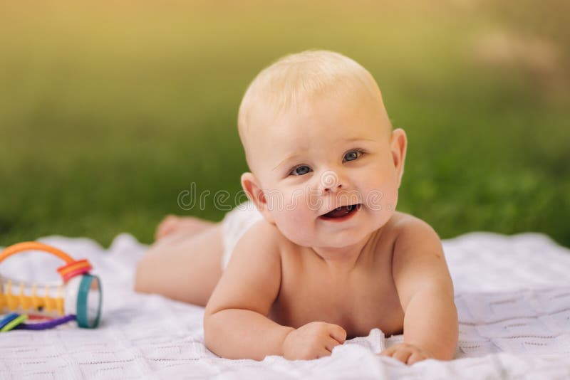 Cute Happy Toddler Lying on a Blanket on the Grass Outdoors in Summer