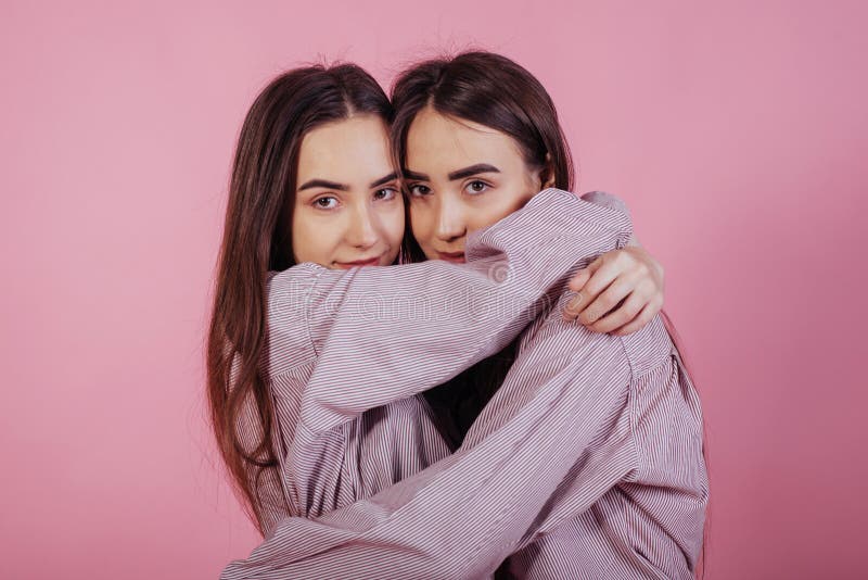 Cute hugs Två systrar står och ställer sig i studion med vit bakgrund arkivfoton