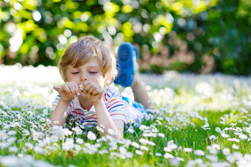 Cute kid boy laying on green grass in summer