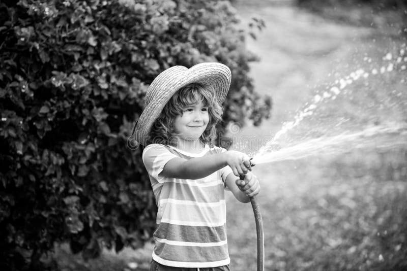 Cute Kid in Straw Hat is Laughing with Water Spraying Hose Stock Image