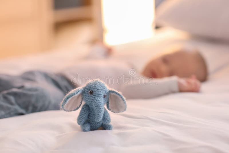 Cute knitted toy on bed near sleeping little boy royalty free stock photography Cute knitted toy on bed near sleeping little boy royalty free stock photography