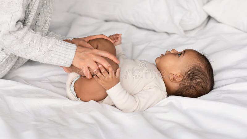 Cute little African American baby playing in bed with mom