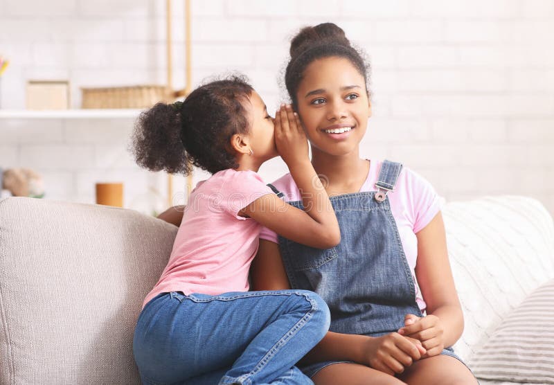 Cute little african girl whispering something to her elder sister ear stock photo Cute little african girl whispering something to her elder sister ear stock photo