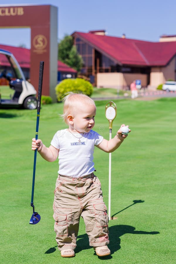 Cute little baby boy playing golf on a field