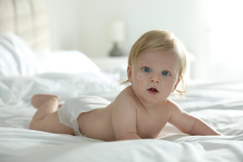 Cute little baby in diaper lying on bed stock images