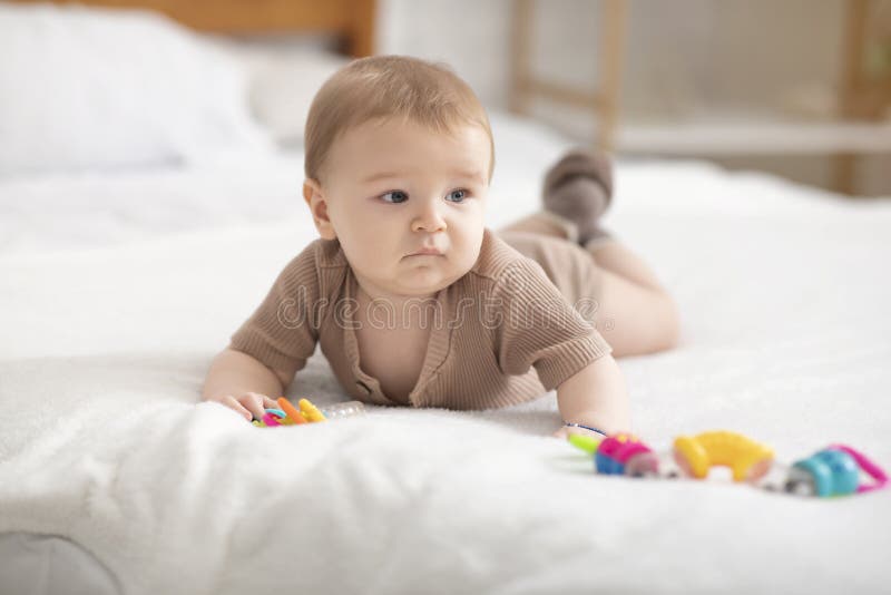 Cute little baby playing with toys on bed