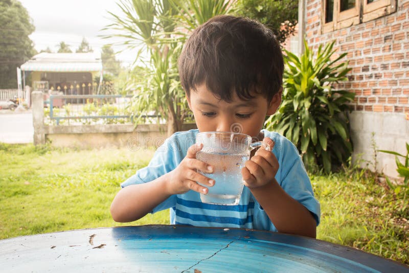 Cute little boy drinking water stock image