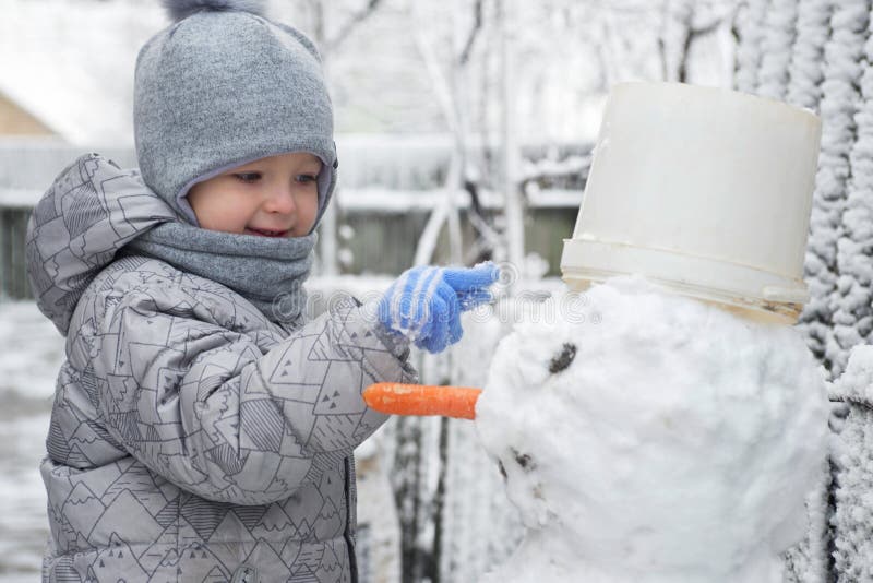 Cute little boy is making a snowman. Child playing with snow. Children wintertime outdoor activitie time concept