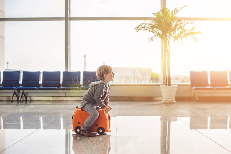 Roztomilý malý chlapec oranžový kufor na letisko.