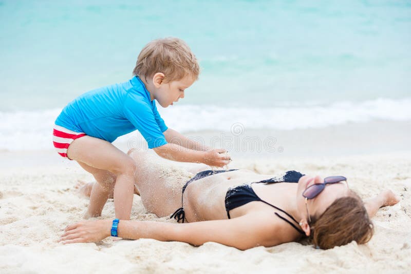 Cute little boy playing with mother on the beach