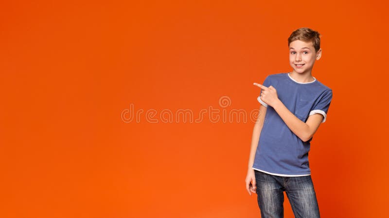 Cute little boy pointing away on orange background