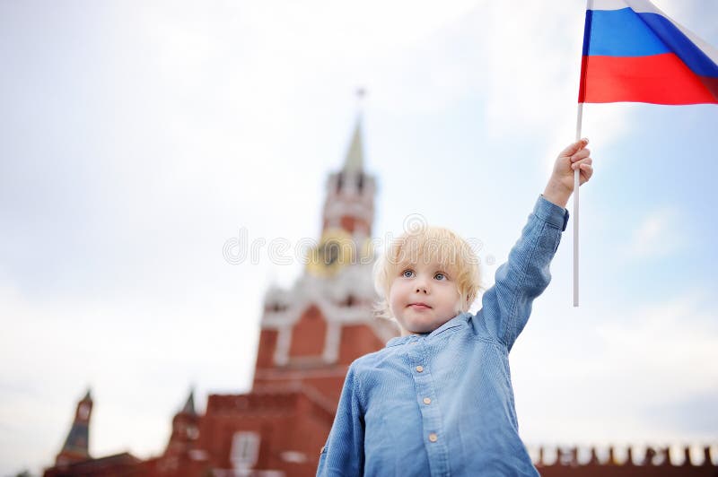 Cute little boy with russian flag with Spasskaya tower Russia, Moscow on background