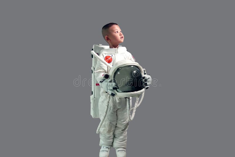 Cute little boy in space suit holding helmet and standing looking up at the sky.