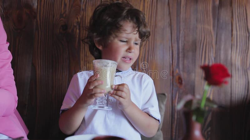 Cute little boy tasting coffee from cup at cafe