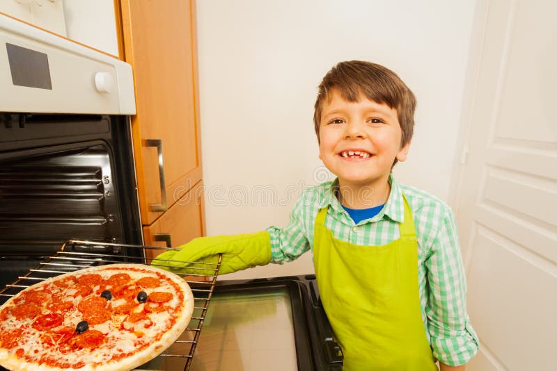 Cute little chef baking tasty pizza in the oven
