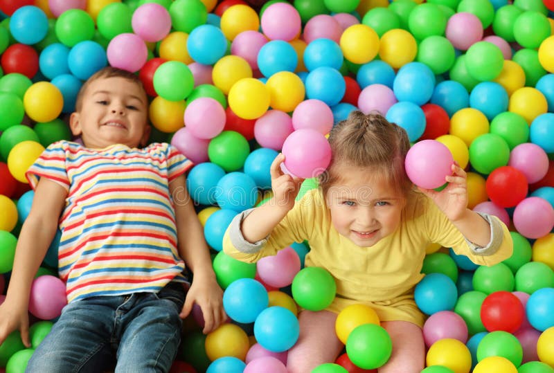 Cute little children playing in ball pit at indoor amusement park