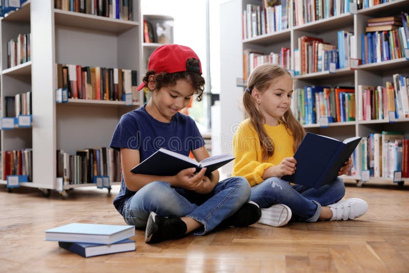 Cute little children reading books on floor royalty free stock images