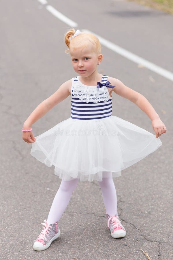 Download A Cute Little Girl In A Beautiful Dress And Sneakers Playing On Stock Photo - Image of risk, child: 83720614