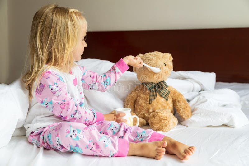 Cute little girl with blonde hair sitting on the bed with stuffed teddy bear. Happy childhood. Stay at home during royalty free stock photos Cute little girl with blonde hair sitting on the bed with stuffed teddy bear. Happy childhood. Stay at home during royalty free stock photos