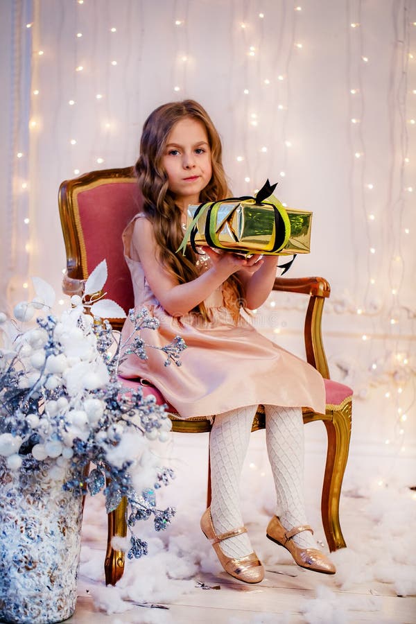 Cute little girl with curly hair with a gift on Christmas Eve, before the New Year