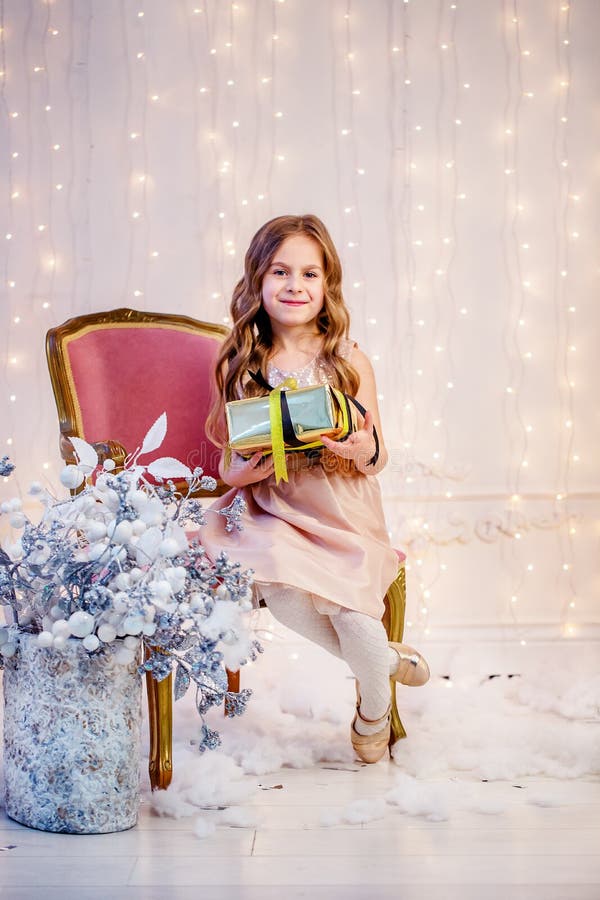 Cute little girl with curly hair with a gift on Christmas Eve, before the New Year