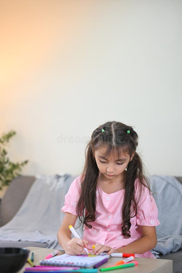 Cute little girl doing homework or drawing activity at home stock photography
