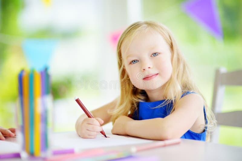 Cute little girl drawing with colorful pencils at a daycare
