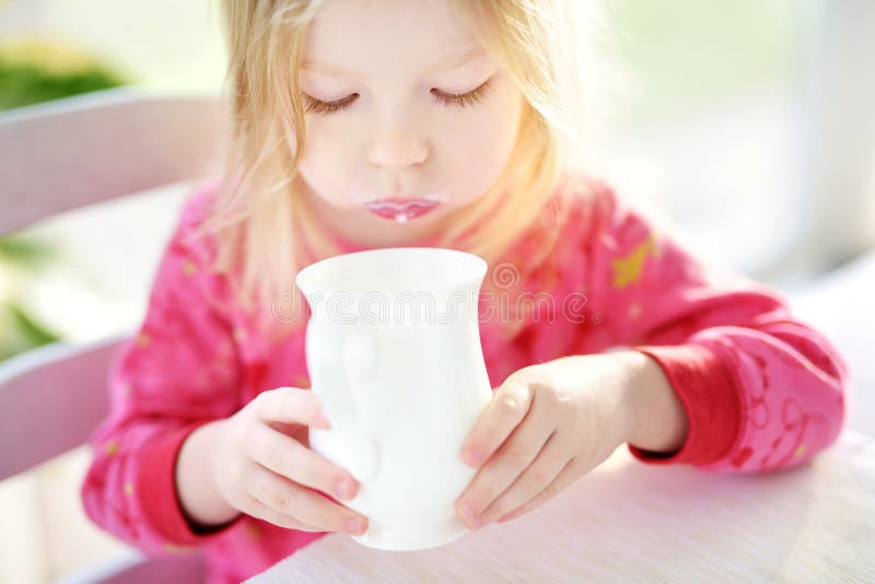Cute little girl drinking fresh organic milk