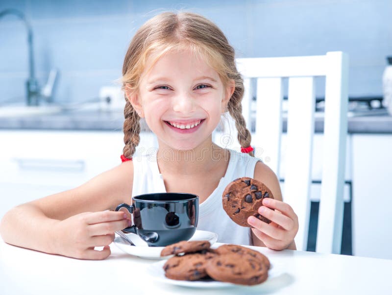 Cute little girl drinking tea with cookies