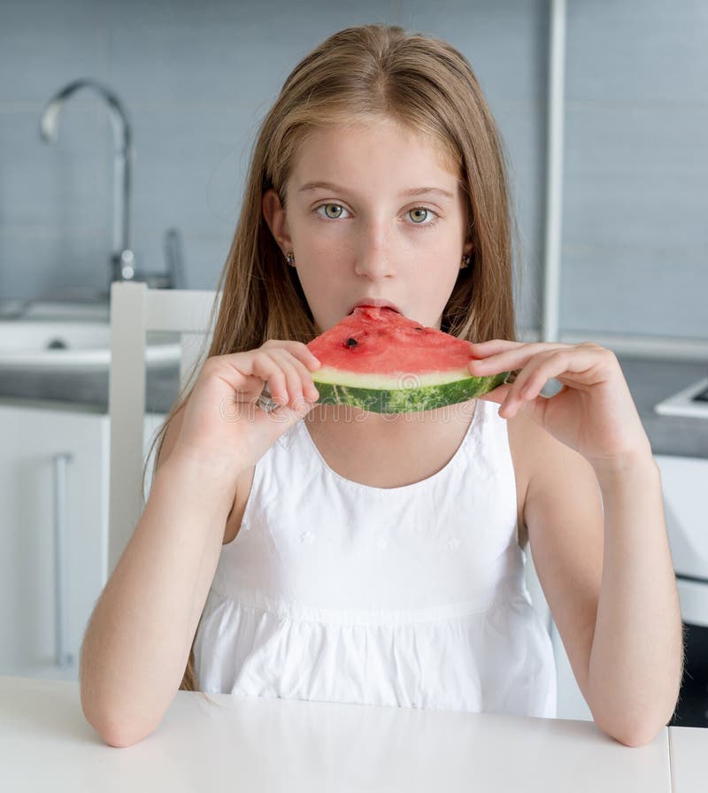 Cute little girl eats a watermelon in the kitchen